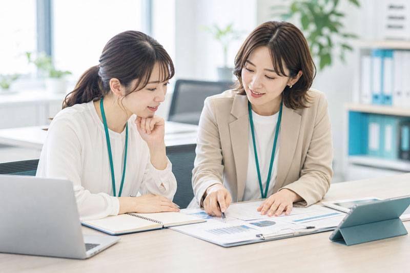 先輩職員と研修資料を確認している様子